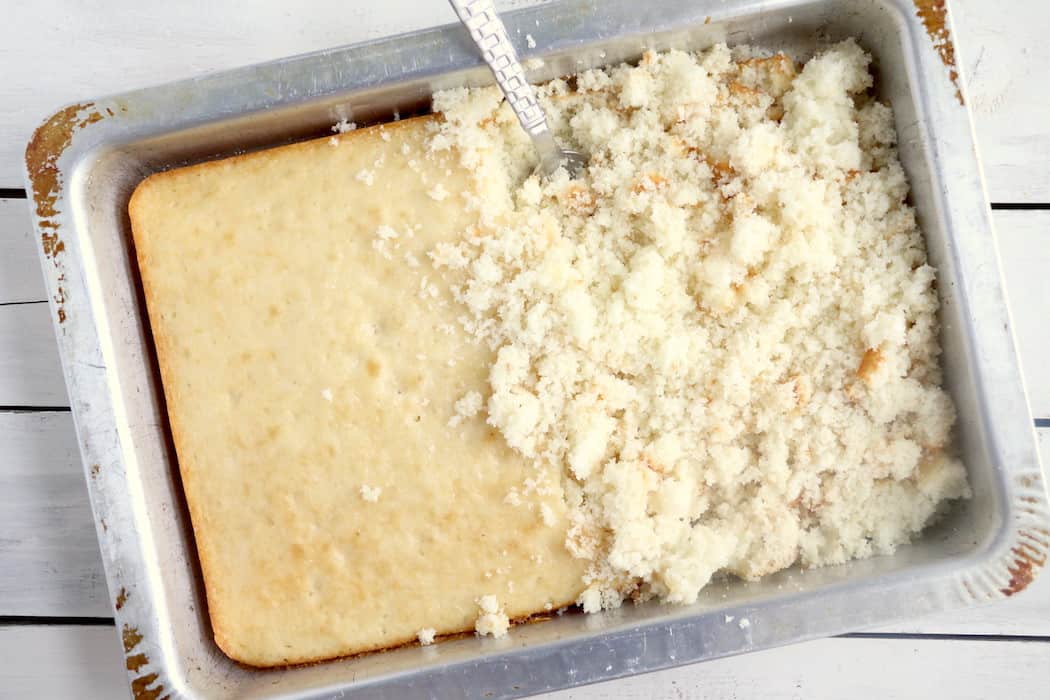 White cake in a cake pan with half the cake crumbled with a fork.