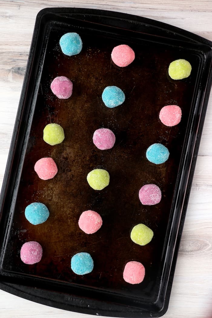 Colorful sugar cookie dough balls on a baking sheet.
