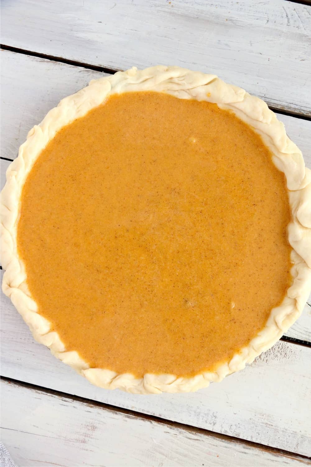 Pumpkin pie crust with filling ready to go into the oven.