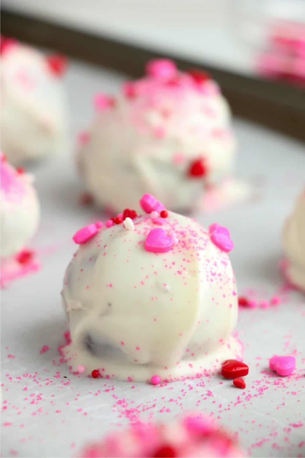 Oreo truffles with pink sprinkles on a baking sheet.