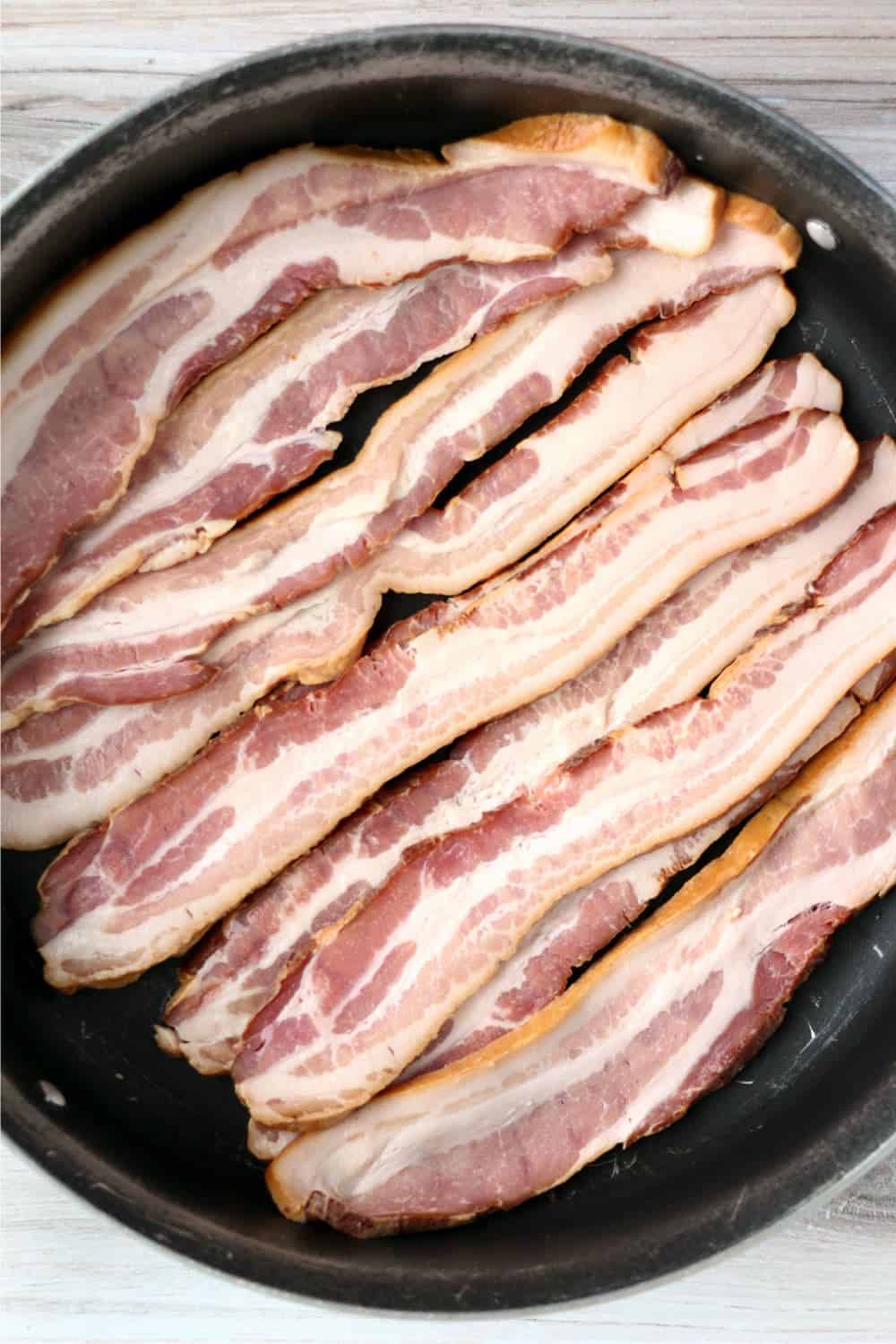 Strips of bacon cooking in a skillet