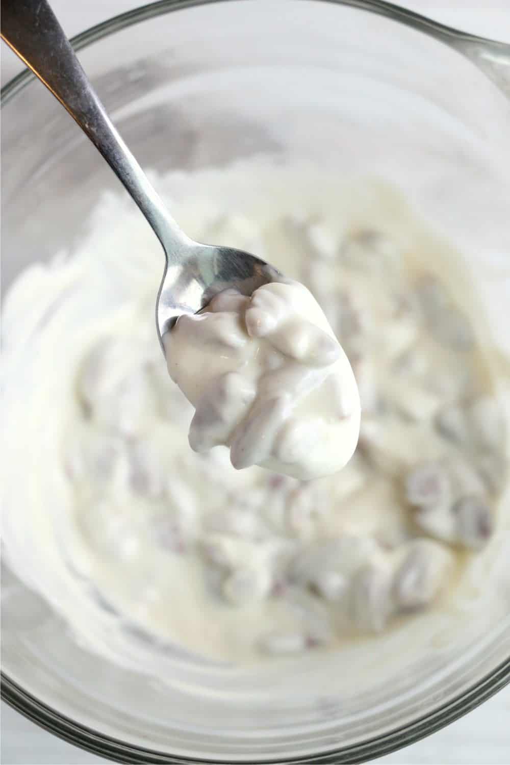 white chocolate and pecan mixture sticking to a spoon above the bowl
