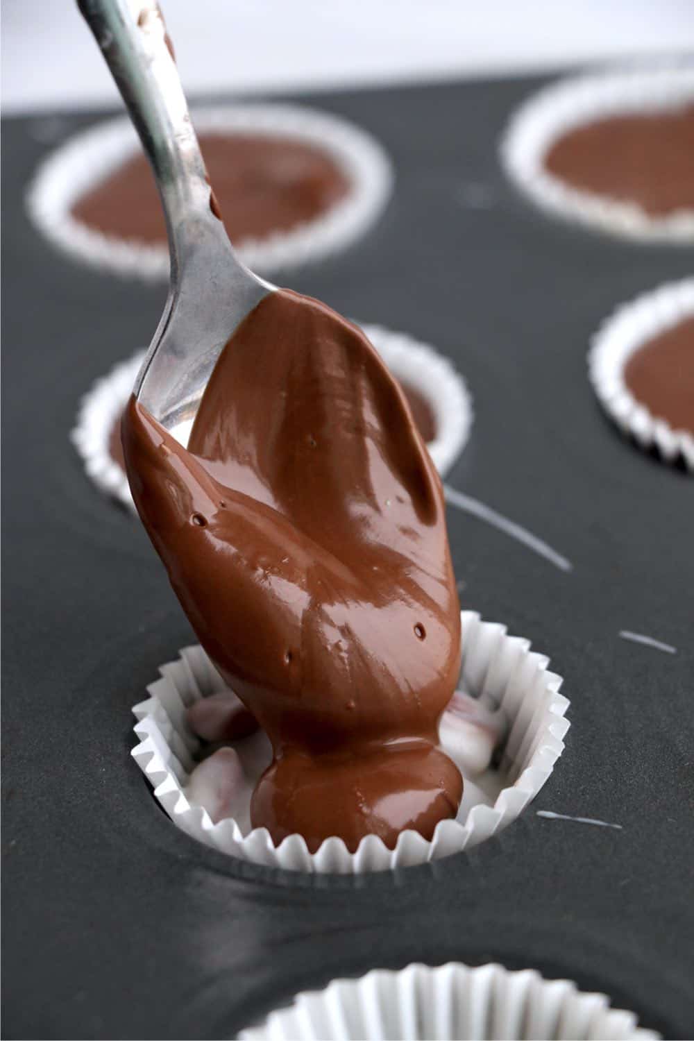 melted milk chocolate being spooned on top of the white chocolate and pecan mixture