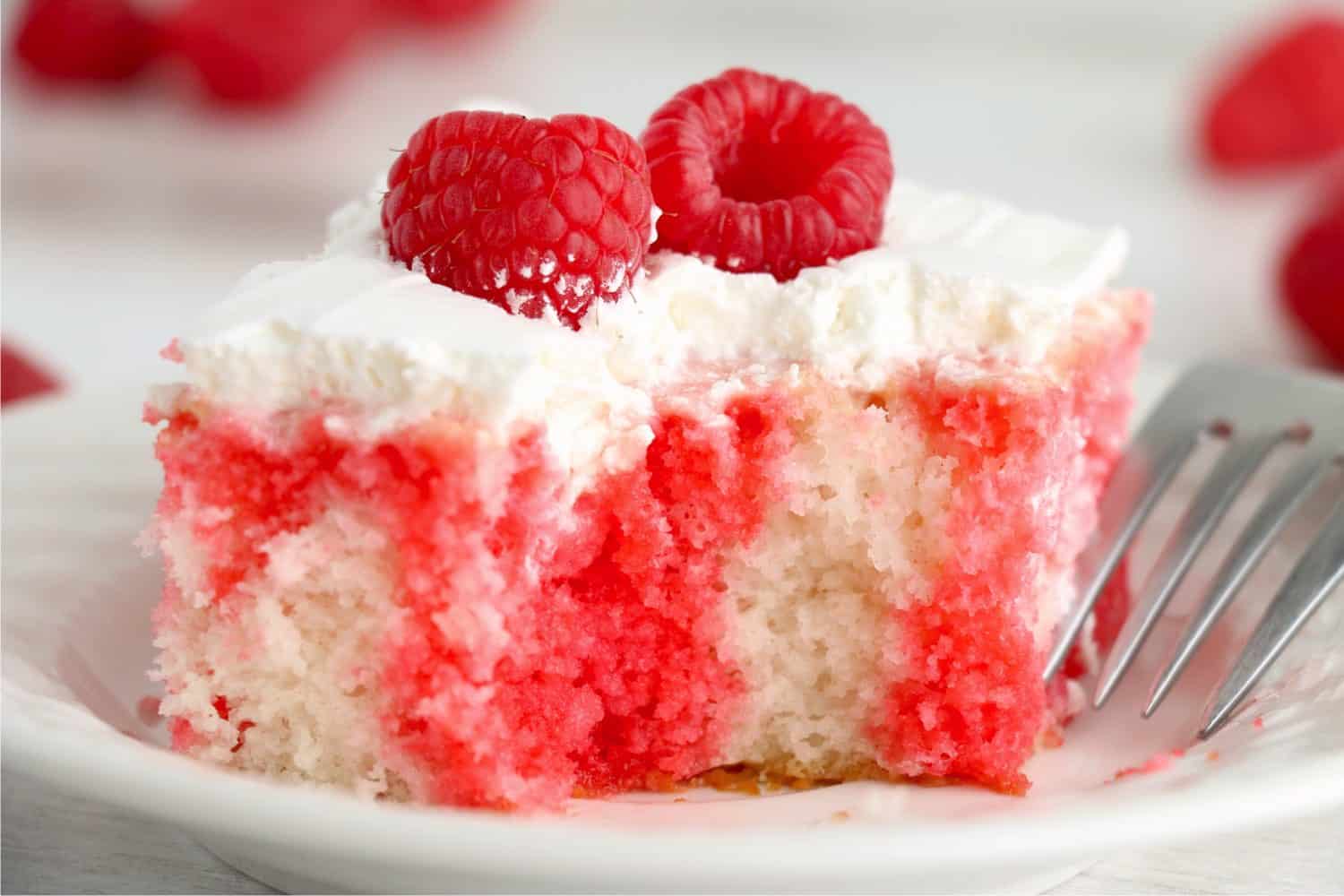A piece of Raspberry Jello Cake on a white plate.