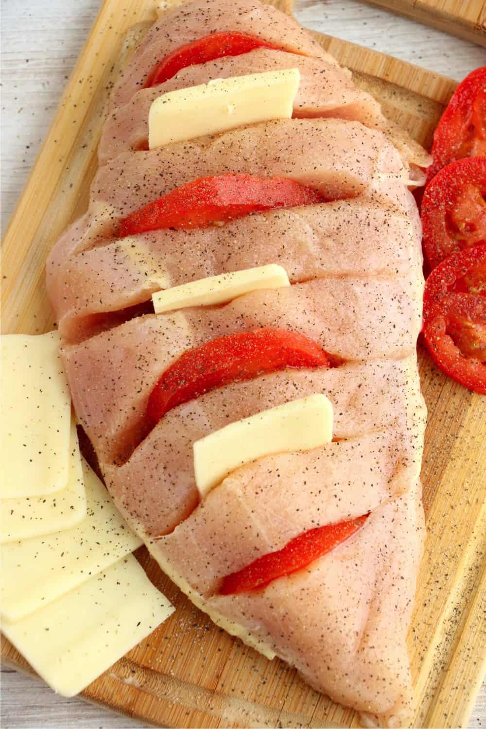 A large chicken breast sliced and stuffed with mozzarella cheese and tomatoes.