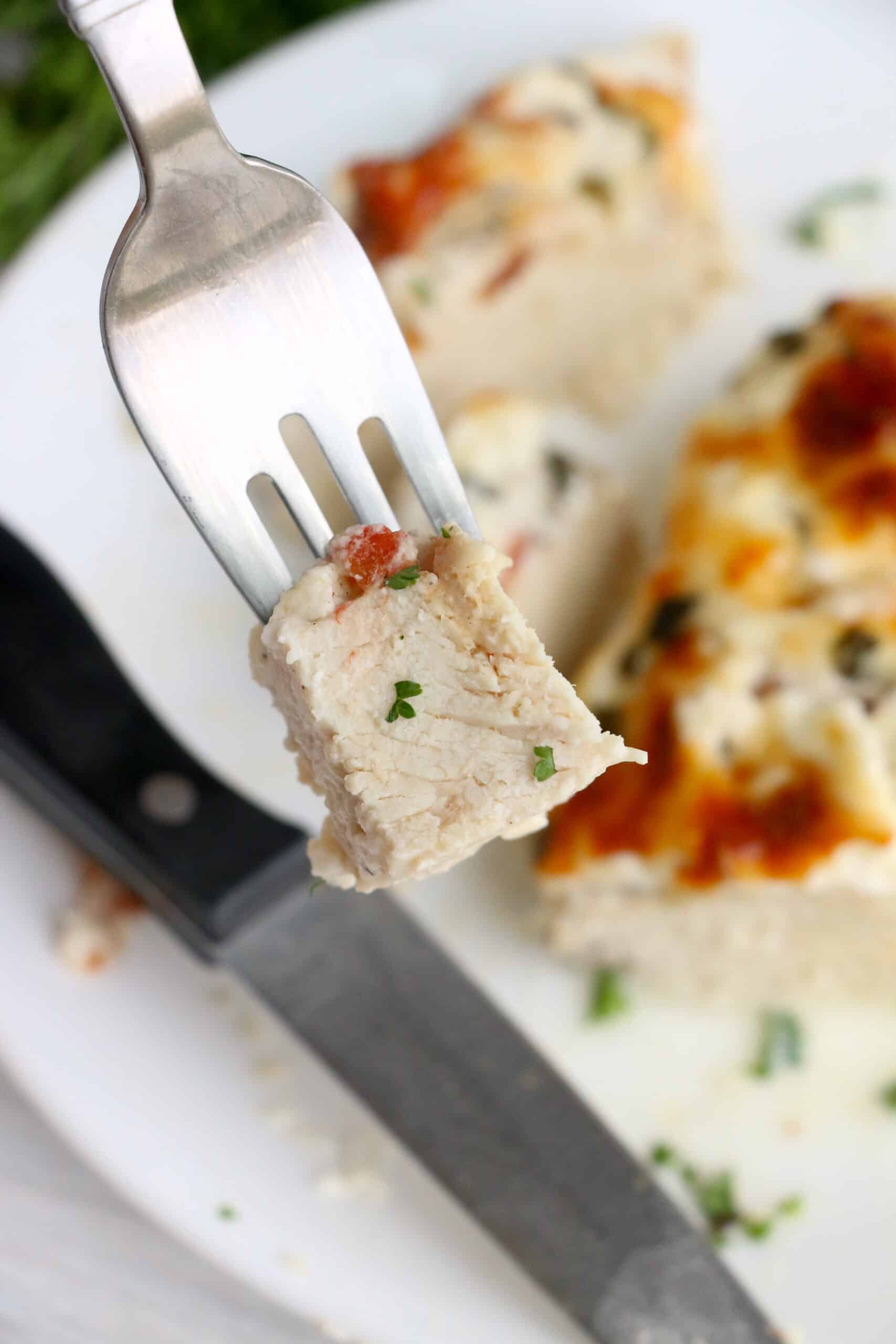 A piece of Caprese Hasselback Chicken on a fork.