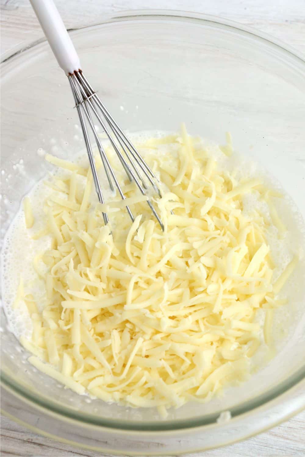 A small mixing bowl with sauce and shredded mozzarella cheese in it.