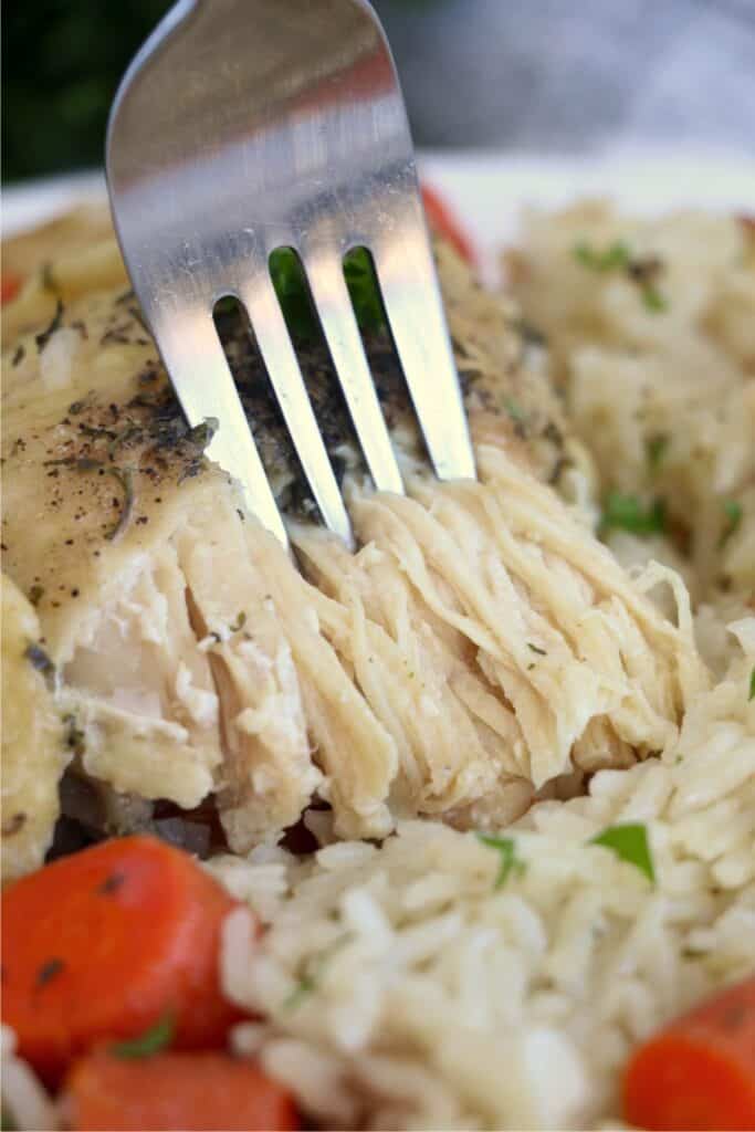 A close-up photo of a fork lifting a bite of chicken cooked in an Instant Pot