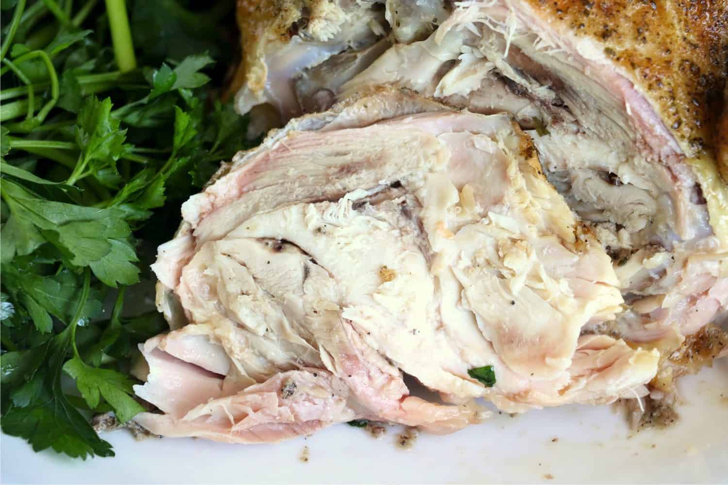 Roasted whole chicken sliced with parsley on the side