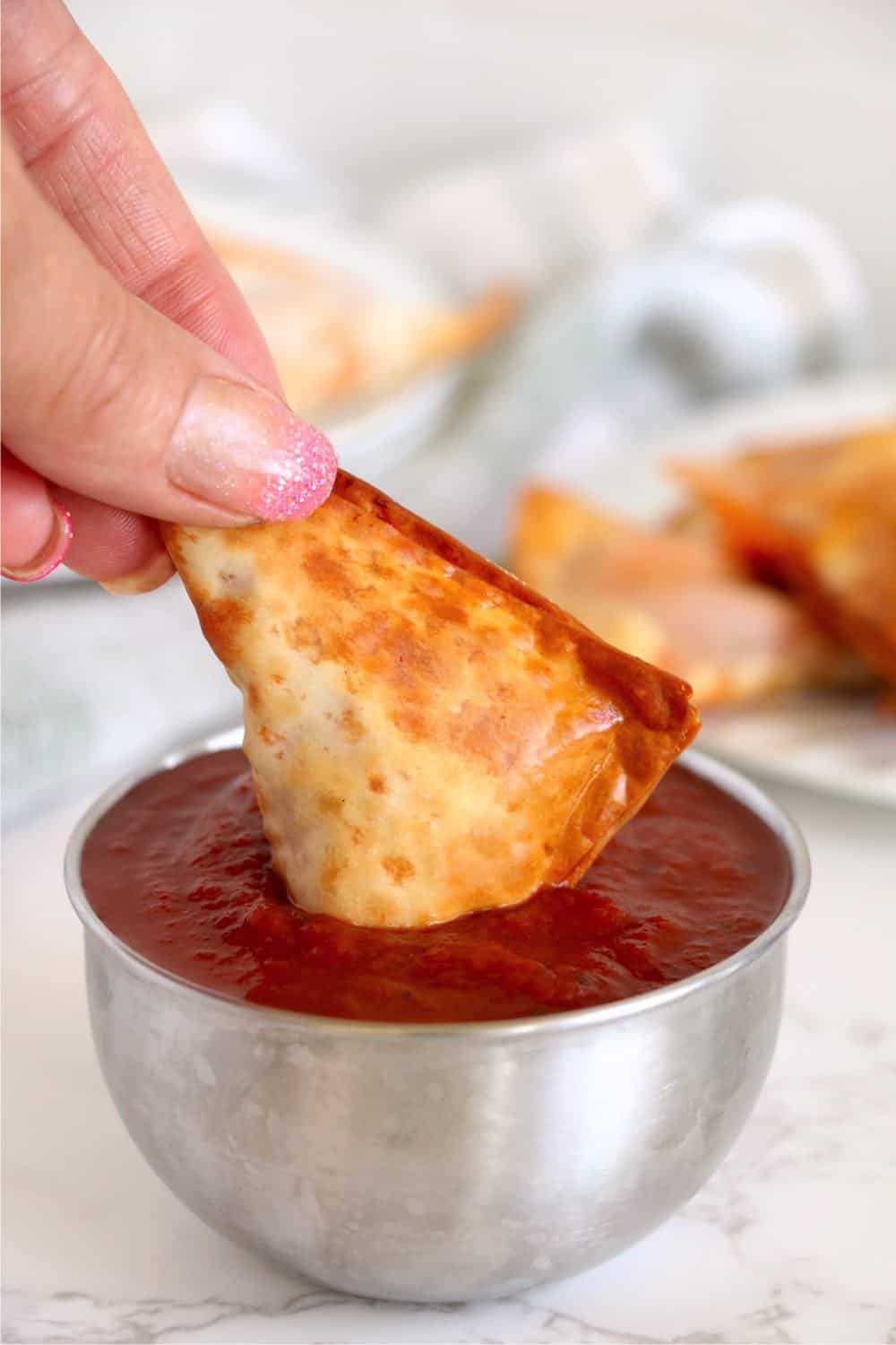 air fried crispy wonton dipped into a small bowl of pizza sauce. 