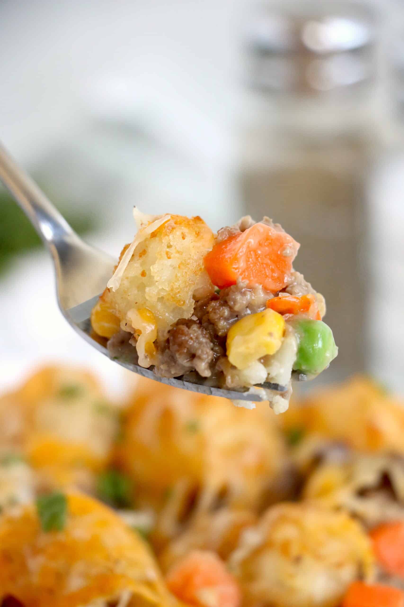 Close up image of Ninja Foodi tater tot casserole on a silver fork in the air. 