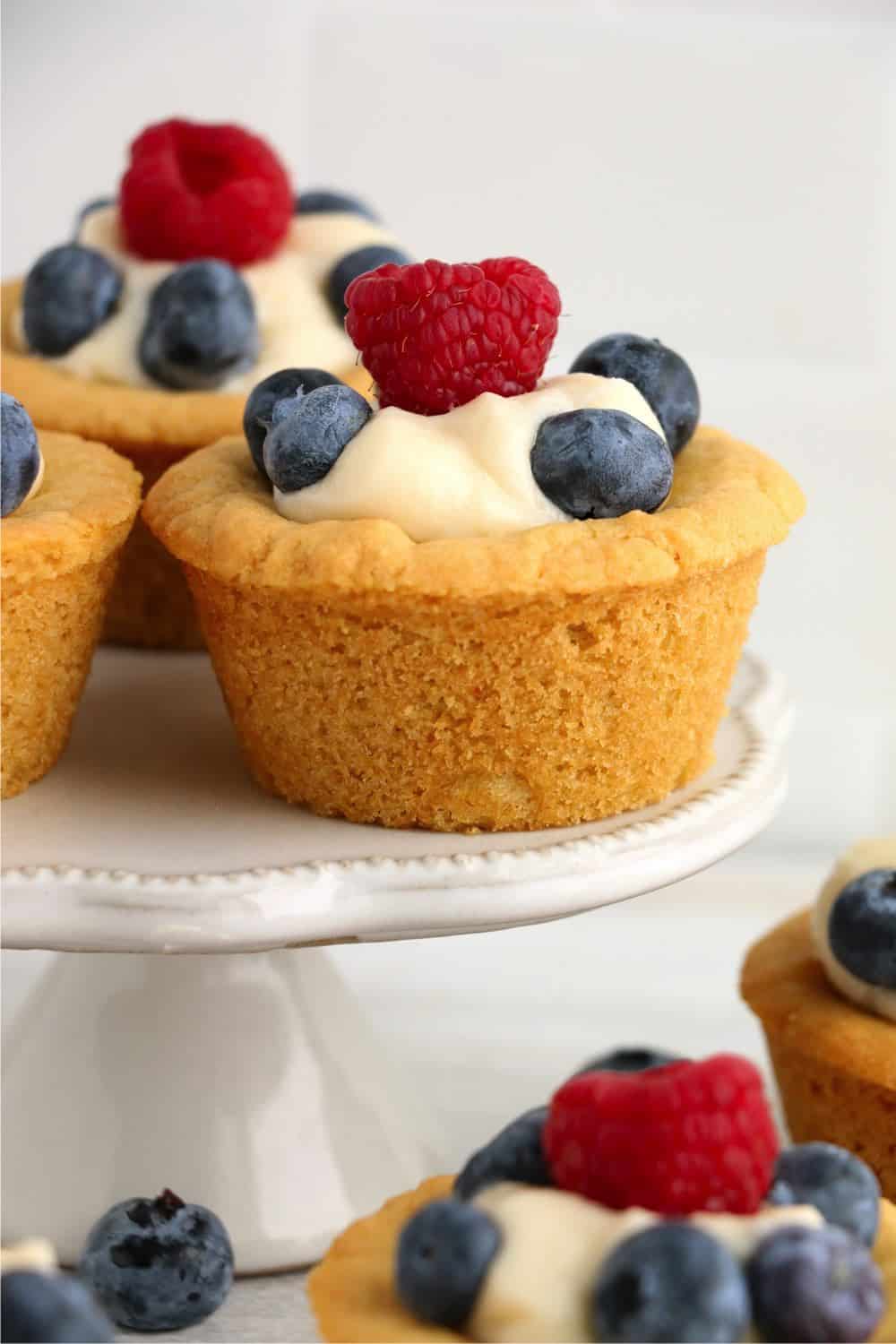 sugar cookie cups filled with cheesecake filling, and then topped with blueberries and raspberries 