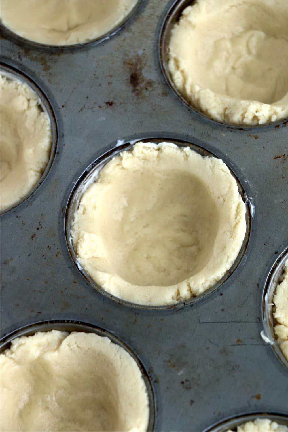 muffin tin with sugar cookie pressed down in it. 