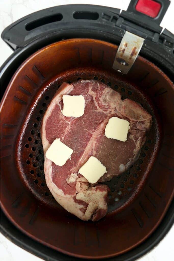 Overhead shot of porterhous steak topped with butter in air fryer