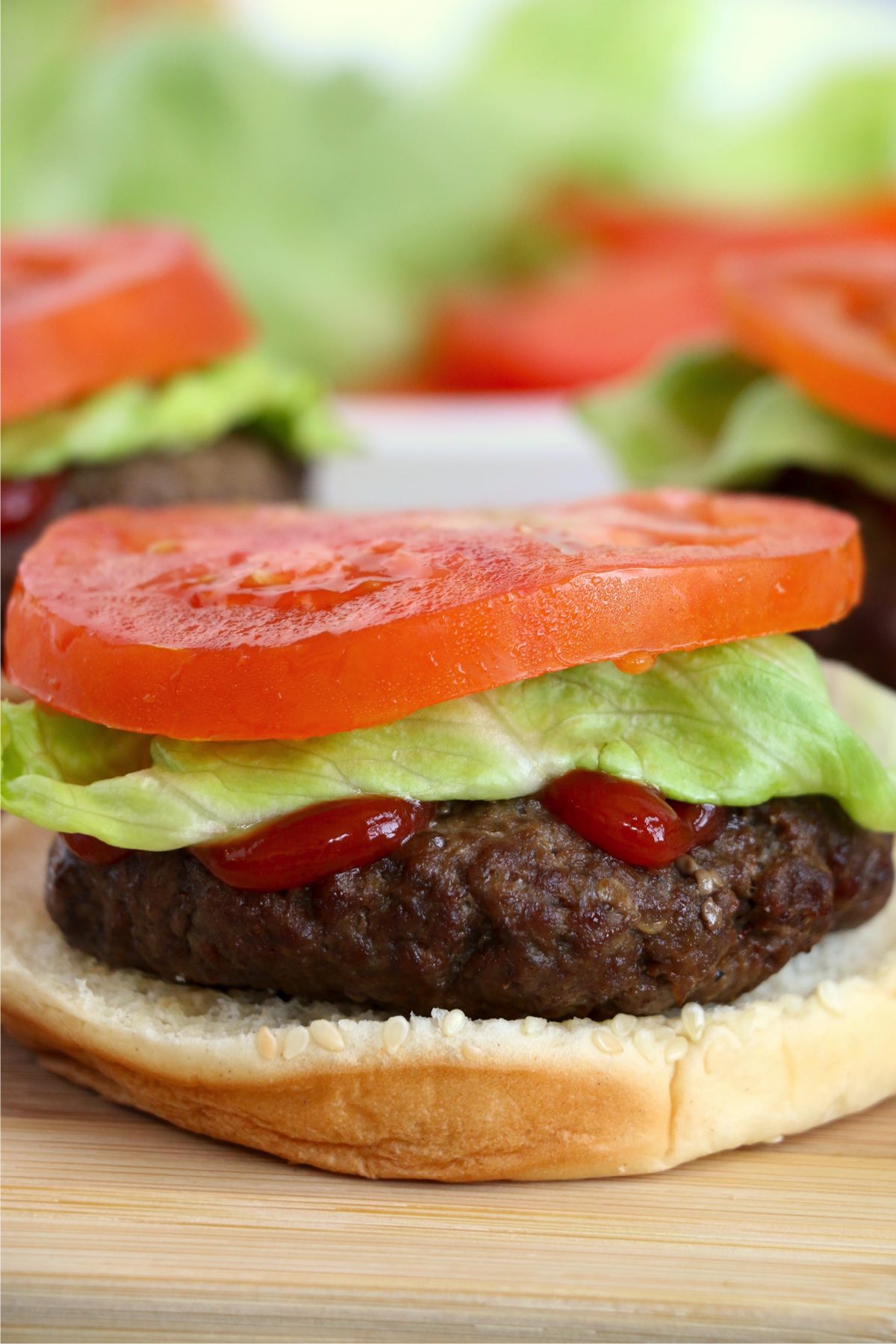 Closeup shot of air fryer hamburger on bun with ketchup, lettuce, and tomato