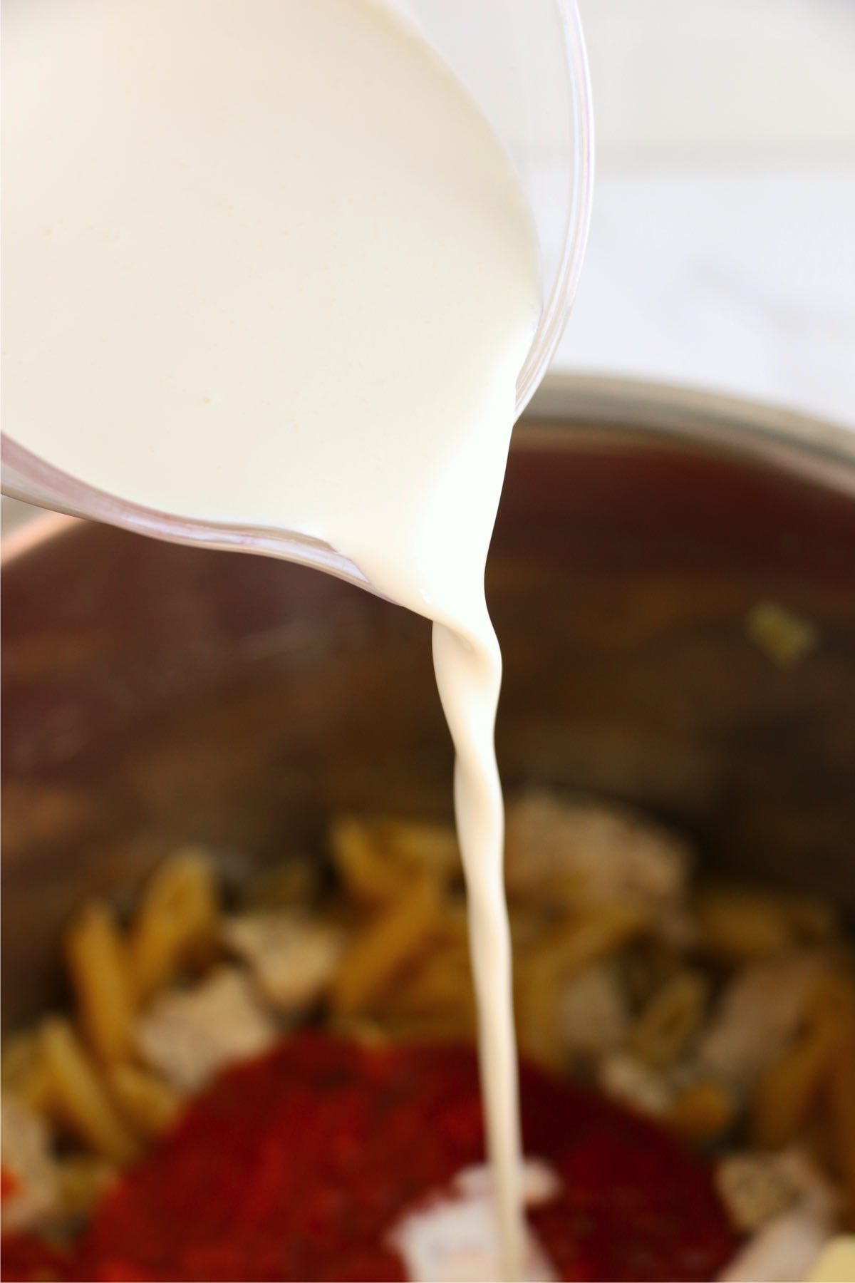 Closeup shot of cream being poured into instant pot