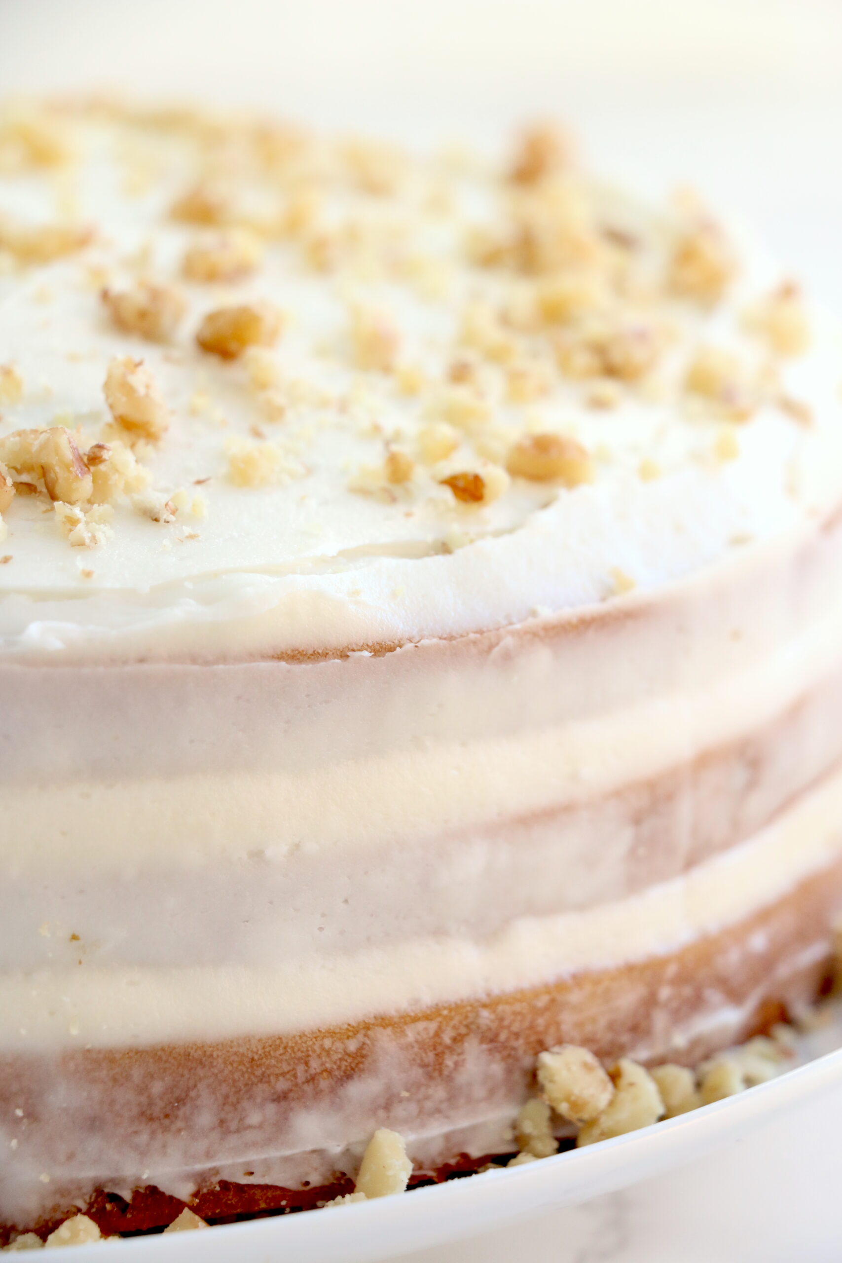 Closeup shot of fully frosted nake carrot cake on cake stand