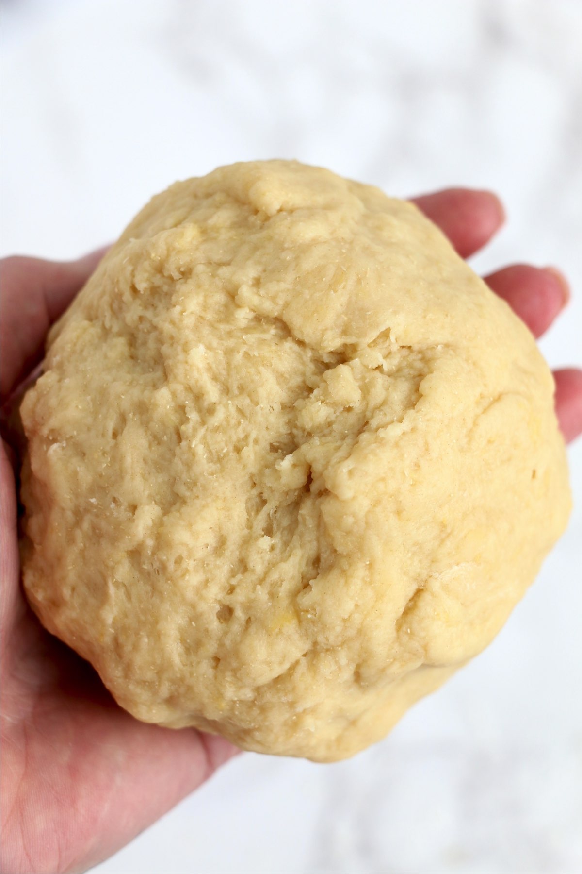 Closeup shot of hand holding cinnamon roll dough