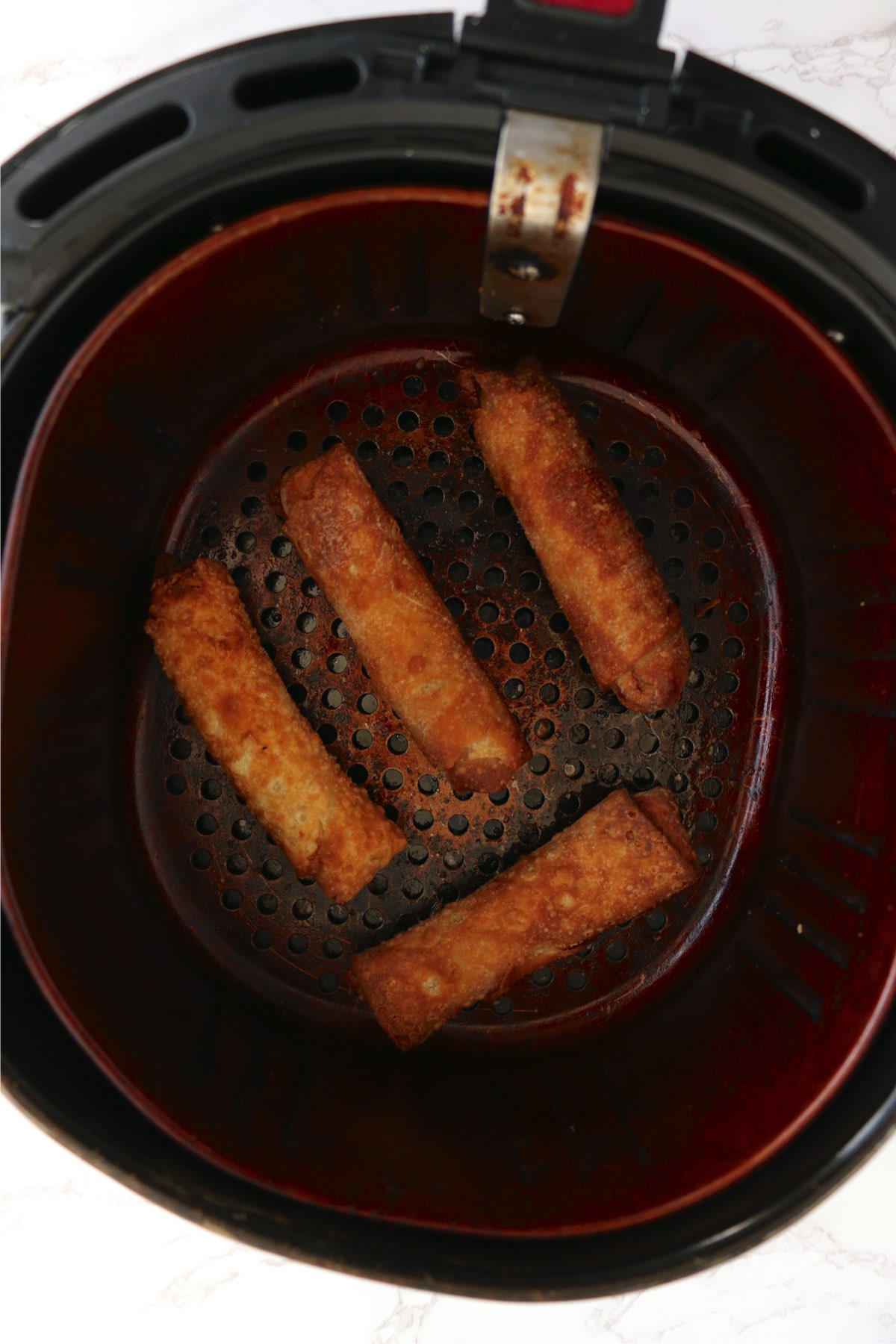 Overhead shot of cooked egg rolls in air fryer basket