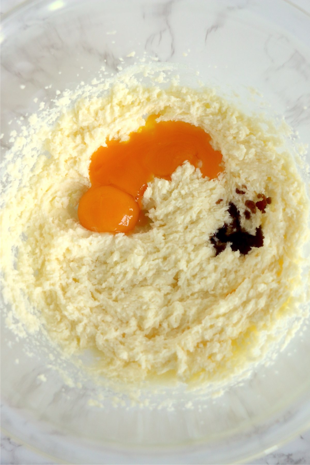 Closeup overhead shot of creamed butter and sugar with eggs and vanilla