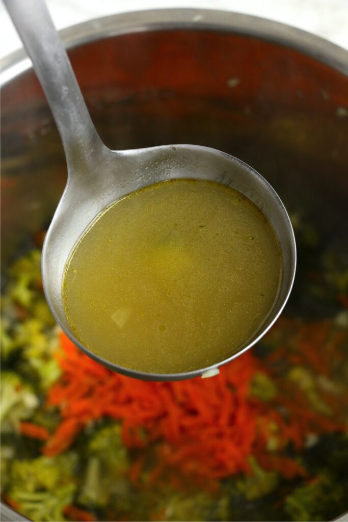 Closeup shot of ladle full of broth over soup