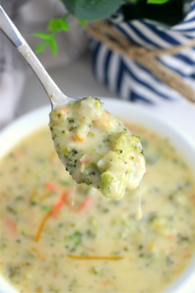 Closeup shot of spoonful of instant pot broccoli cheddar soup over bowl of more soup