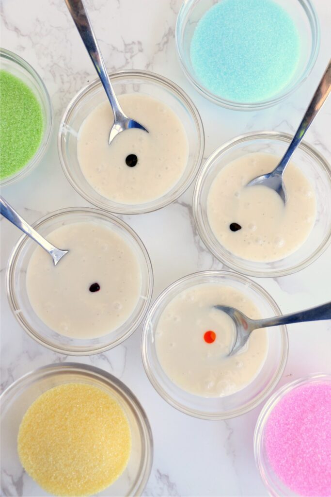 Overhead shot of bowls of icing with a dot of food coloring in each