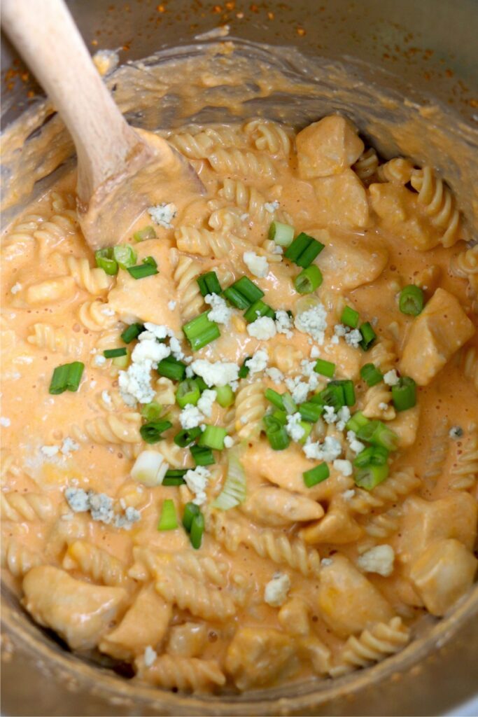 Instant pot buffalo chicken pasta in instant pot topped with blue cheese and chopped green onions