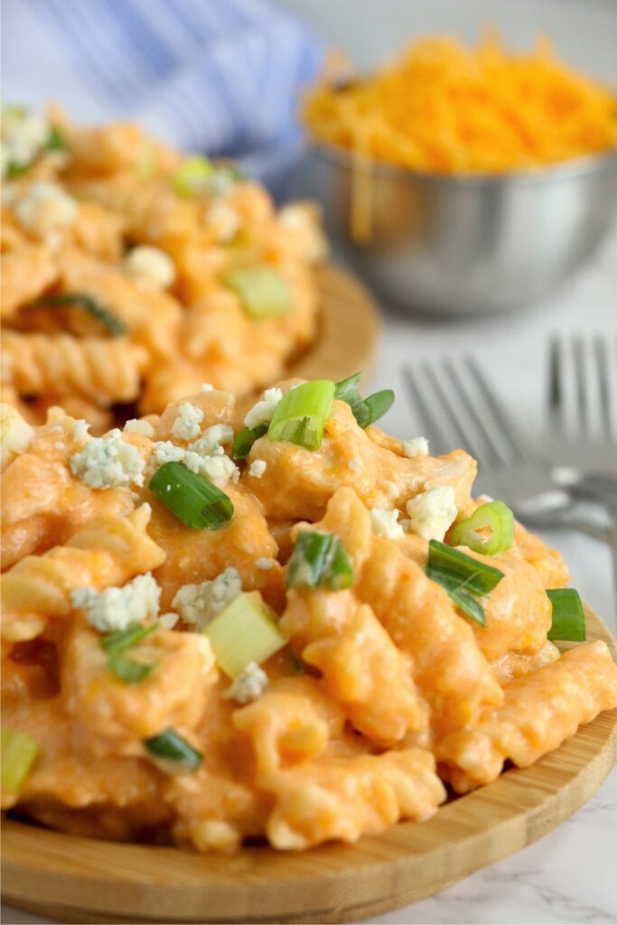 Instant pot buffalo chicken pasta in bowl wiht more buffalo chicken pasta in background