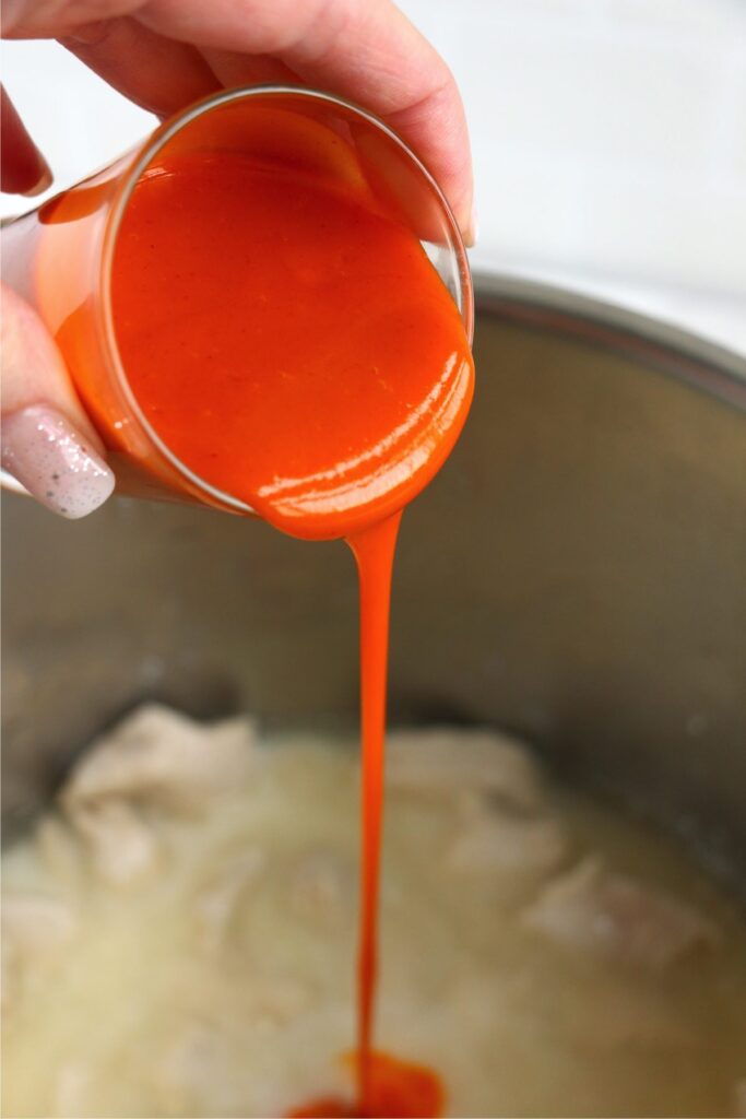 Buffalo sauce being poured into instant pot