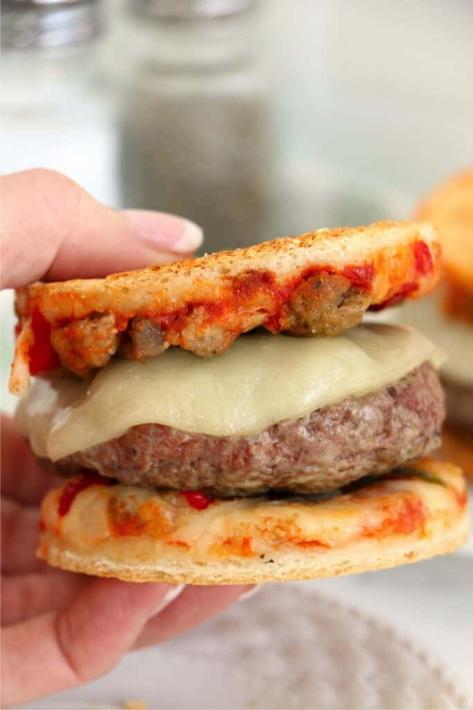 Closeup shot of hand holding a frozen pizza burger