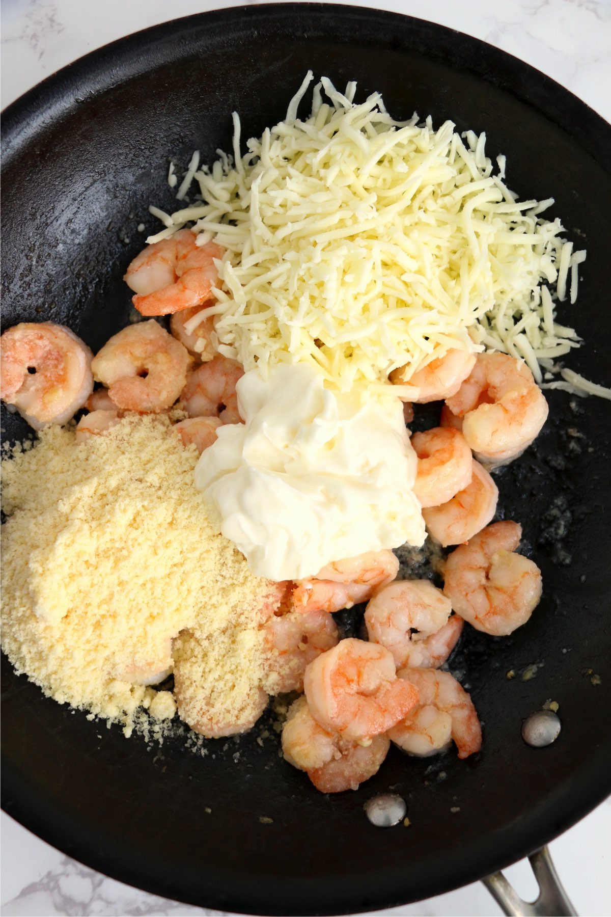Closeup shot of shrimp, mayonnaise, parmesan, and mozzarella cheese in pan