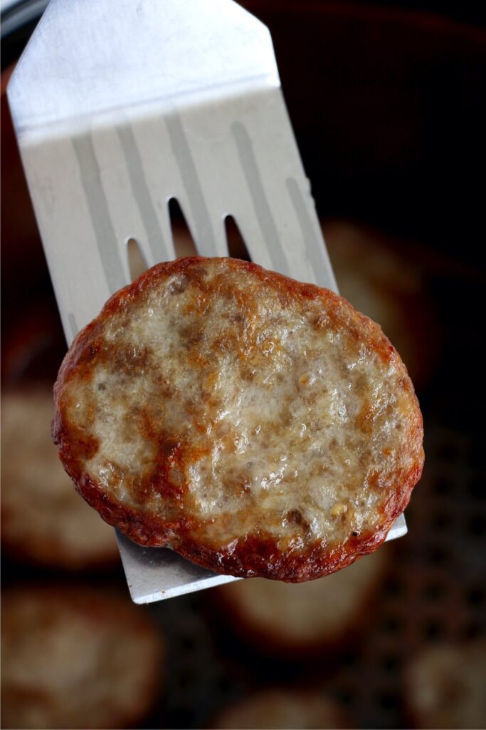 Air fryer frozen sausage patty on spatula