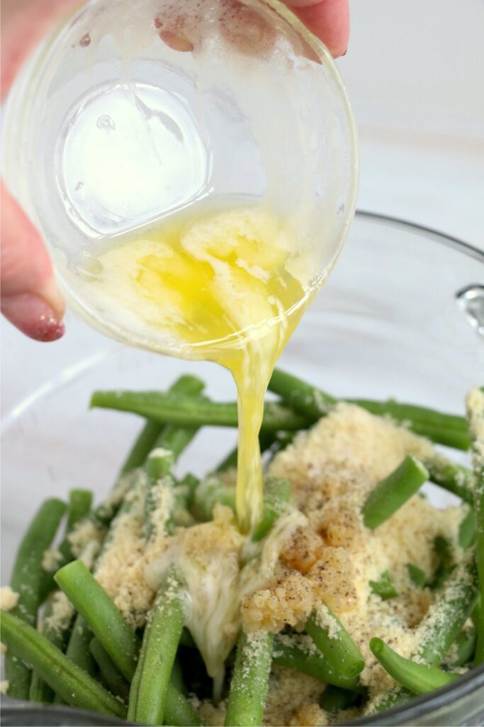 Green beans topped with parmesan cheese, butter, and spices in bowl