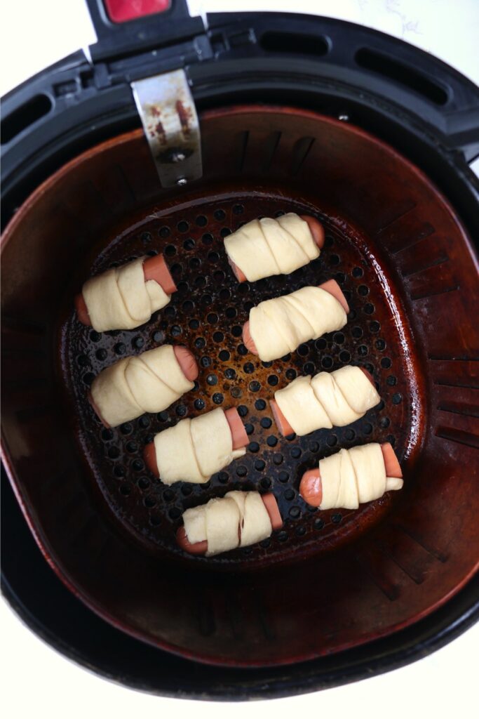 Overhead shot of uncooked pigs in a blanket in air fryer basket