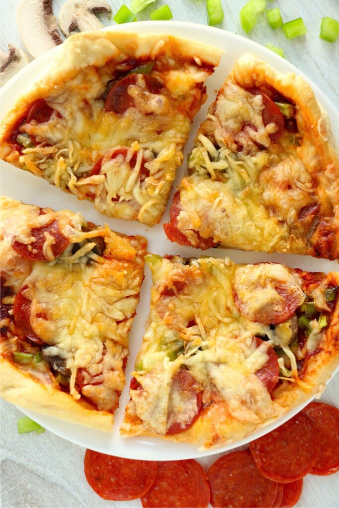 Overhead shot of air fryer pizza cut into four slices on plate