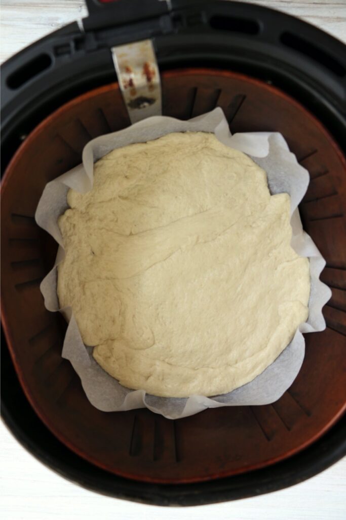 Overhead shot of pizza dough in air fryer basket