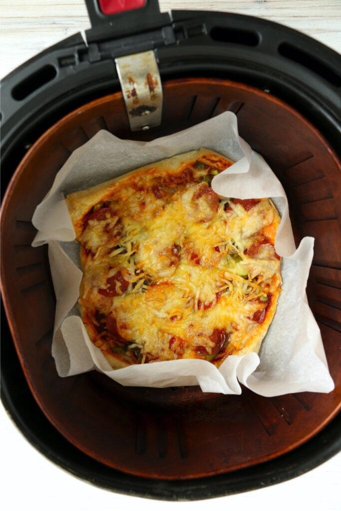 Overheat shot of cooked pizza in air fryer basket