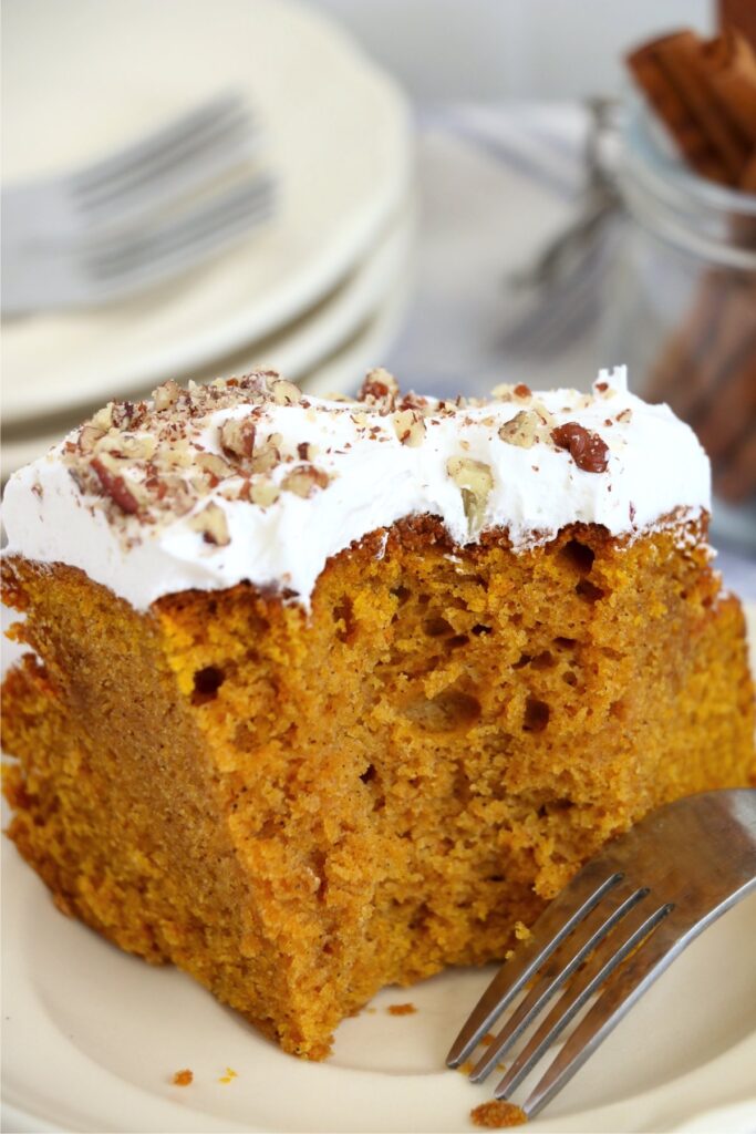 Closeup shot of slice of air fryer pumpkin cake with bite taken out on plate.