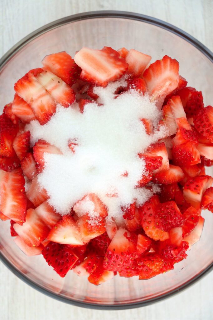 Overhead shot of chopped strawberries and sugar in bowl