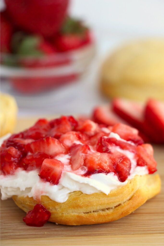 Closeup shot of bottom of biscuit topped with whipped topping and chopped strawberries