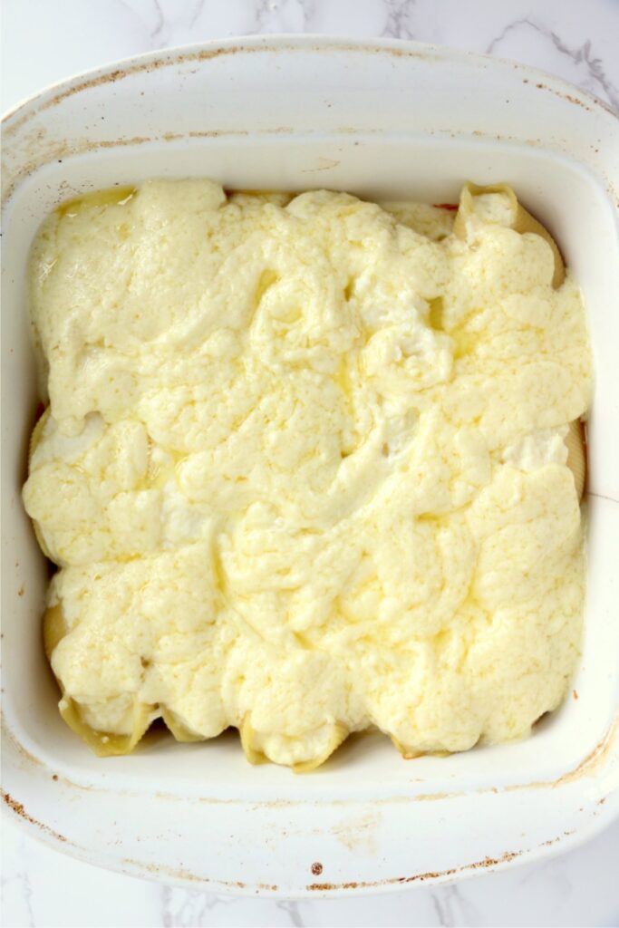 Overhead shot of cheese mixture spread over shells in baking dish