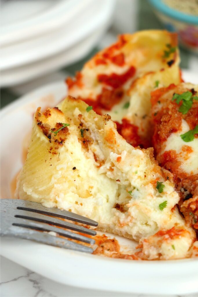 Closeup shot of copycat Olive Garden stuffed shells on plate with fork.
