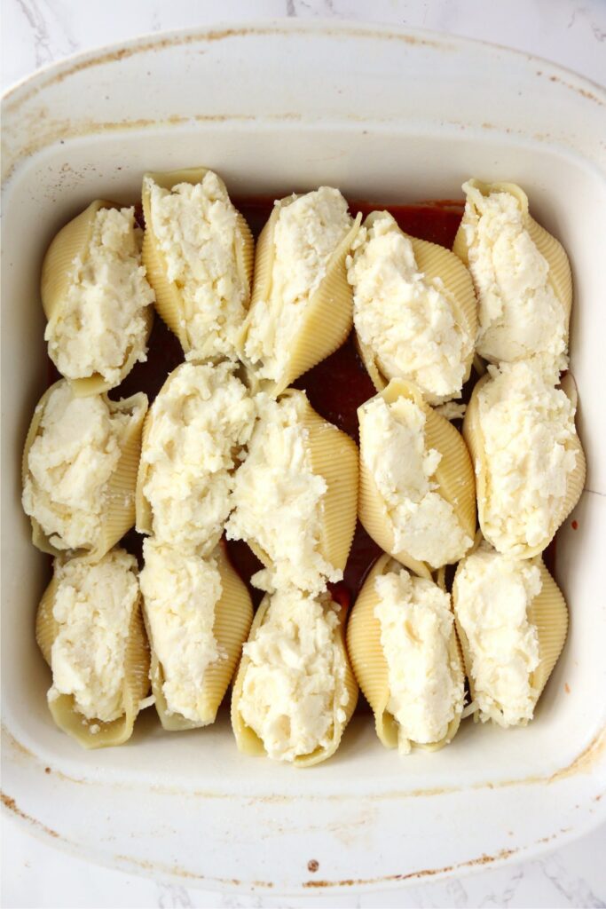 Overhead shot of stuffed shells on top of spaghetti sauce in baking dish