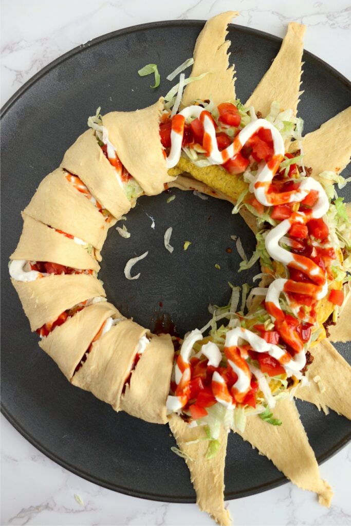 Overhead shoth of crescent roll dough being folded over taco ingredients to form the crescent ring