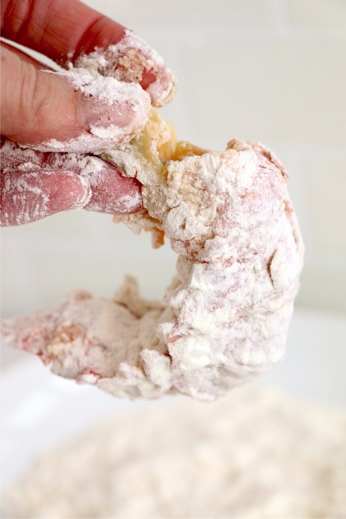 Closeup shot of hand holding lobster tail that's been dipped in milk and flour