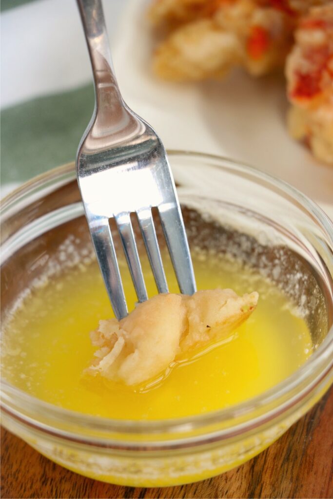 Closeup shot of forkful of fried lobster tails being dipped in butter