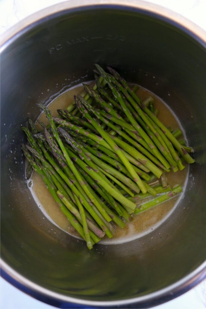 Overhead shot of asparagus with butter and garlic mixture in instant pot