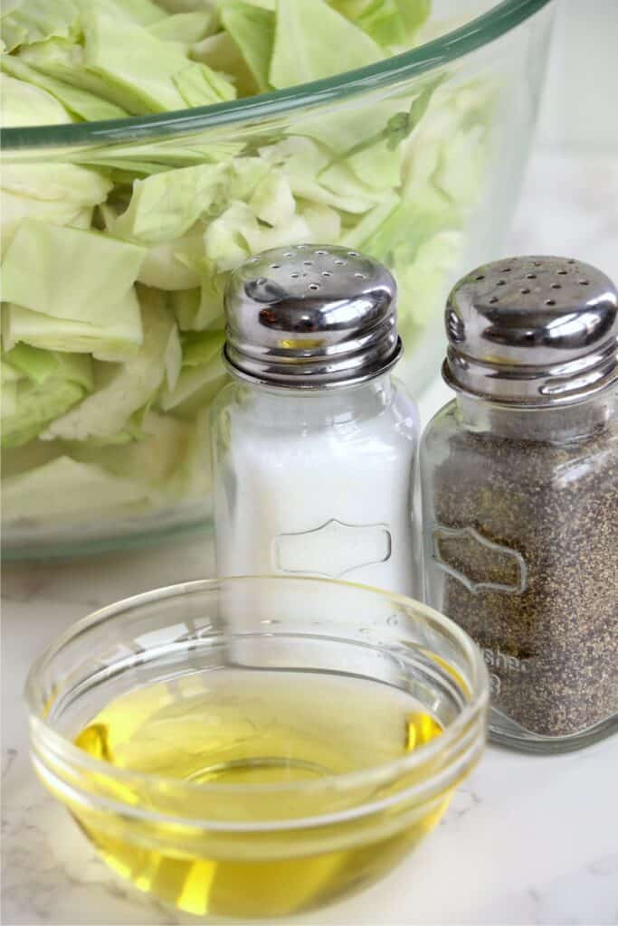 Closeup shot of oil in a small bowl next to salt and pepper shakers