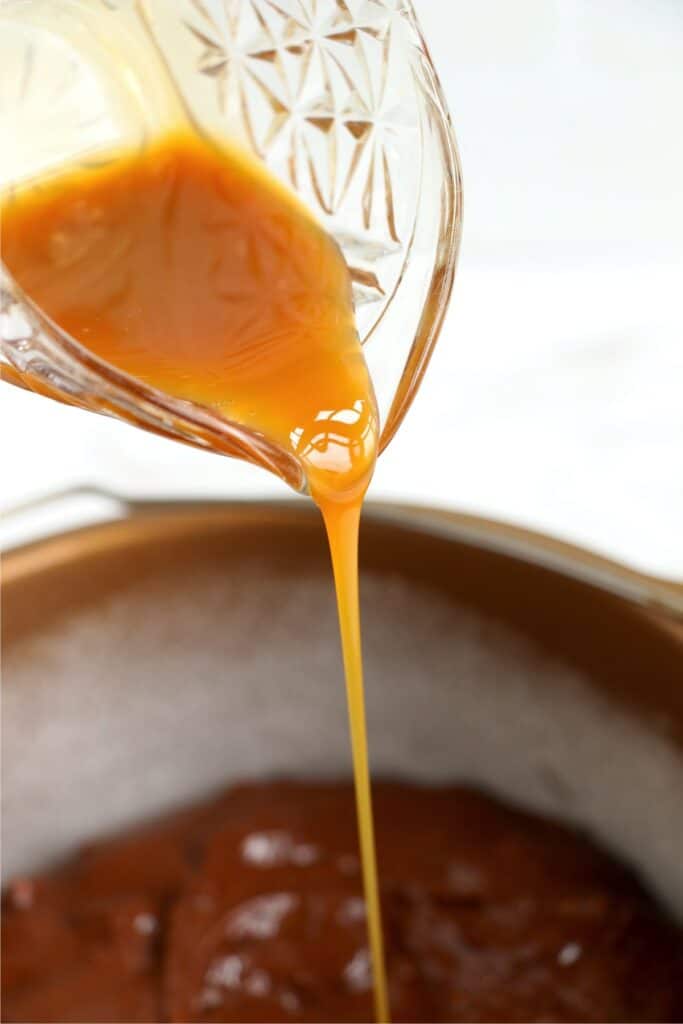 Caramel sauce being poured into brownie batter